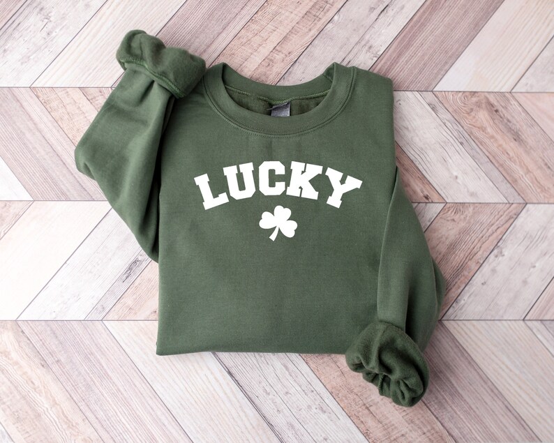 Peut inclure: Un sweat-shirt vert avec le mot "LUCKY" en lettres blanches et un tr&egrave;fle blanc.