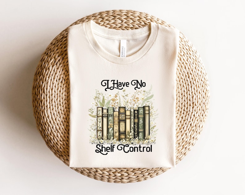 May include: Cream-colored t-shirt with the text "I Have No Shelf Control" above a graphic of vintage books and floral accents. The design features a collection of antique books in various colors, surrounded by delicate botanical illustrations.
