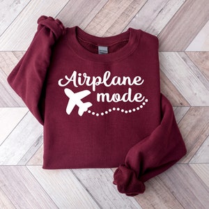 May include: A maroon sweatshirt with a white airplane graphic and the text "Airplane mode" in white.