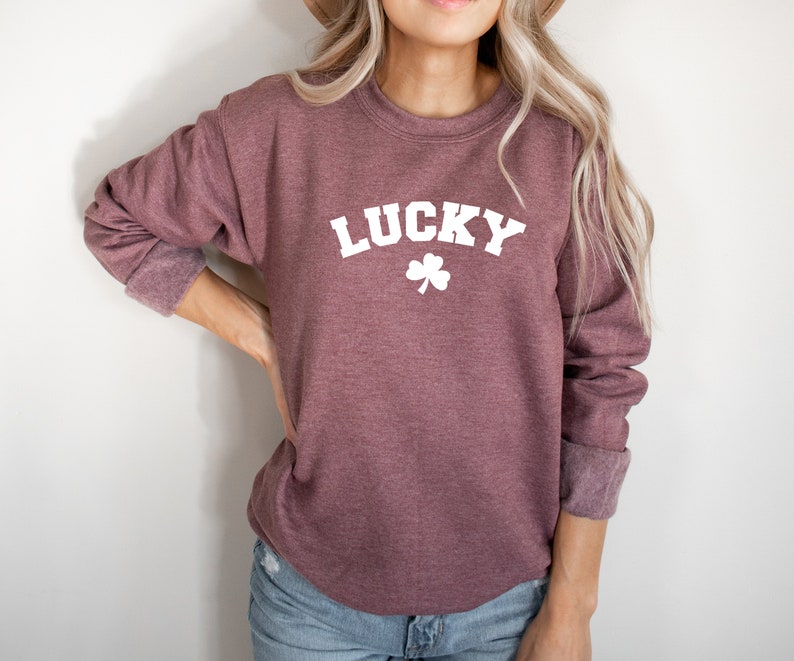 Peut inclure: Un sweat-shirt marron avec le mot "LUCKY" en blanc et un tr&egrave;fle blanc en dessous.
