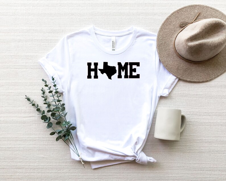May include: White t-shirt with a black outline of the state of Texas and the word "HOME" printed on it.