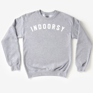 Puede incluir: Una sudadera gris con la palabra "INDOORSY" impresa en blanco en la parte delantera.