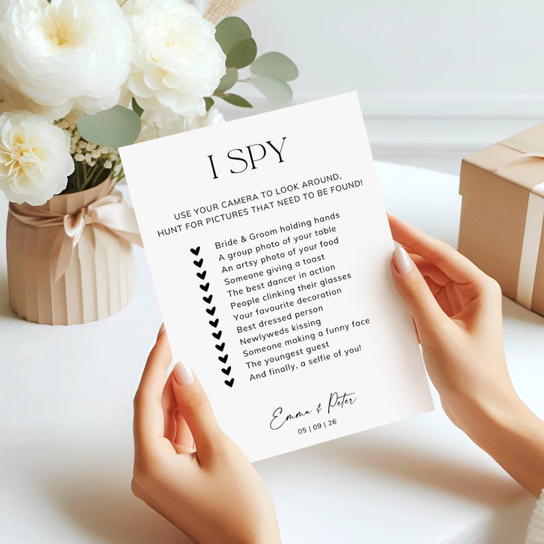 May include: A white rectangular card featuring the black text I SPY, instructions to use a camera, and a checklist of wedding-themed photo prompts. The card includes the names Emma & Peter and the date 05 | 09 | 26 at the bottom.