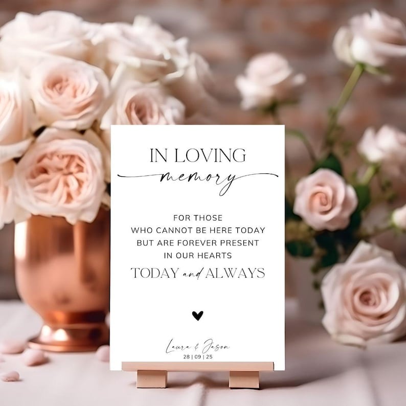 May include: A white rectangular sign on a small stand featuring the black text IN LOVING MEMORY FOR THOSE WHO CANNOT BE HERE TODAY BUT ARE FOREVER PRESENT IN OUR HEARTS TODAY and ALWAYS with a small heart icon and the names Laura and Jason 28 | 09 | 25.