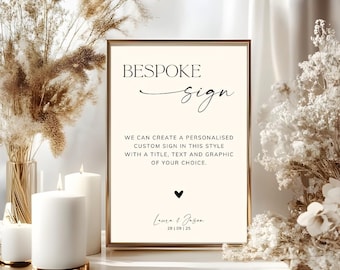 May include: A rectangular sign in a thin gold frame with a cream background. The text reads: BESPOKE sign, WE CAN CREATE A PERSONALISED CUSTOM SIGN IN THIS STYLE WITH A TITLE, TEXT AND GRAPHIC OF YOUR CHOICE, a small heart, Laura & Jason, 28 | 09 | 25.