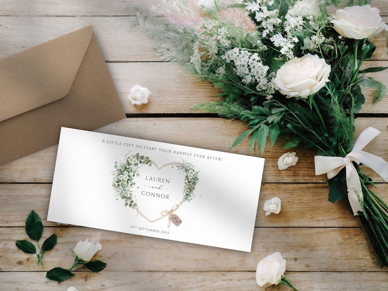 Op de afbeelding: Een trouwuitnodigingskaart met een hartvormig bloemendesign, de namen "Lauren en Connor" en de datum "16 september 2023". De kaart ligt op een houten oppervlak met een boeket witte rozen en groen, en een bruine envelop.
