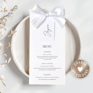 May include: A white menu card with a white ribbon and a tag that says "Joyce". The menu is on a wooden plate. The menu includes the words "MENU", "STARTER", "MAIN COURSE", and "DESSERT". A round sticker with the words "CHANGE MY COLOURS" is on the right.