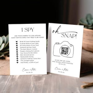 May include: Two white rectangular wedding cards with black text. The left card reads I SPY with a list of photo tasks. The right card reads oh SNAP! with a line-art camera icon, a QR code, and the names Emma & Peter with the date 05 | 09 | 26.