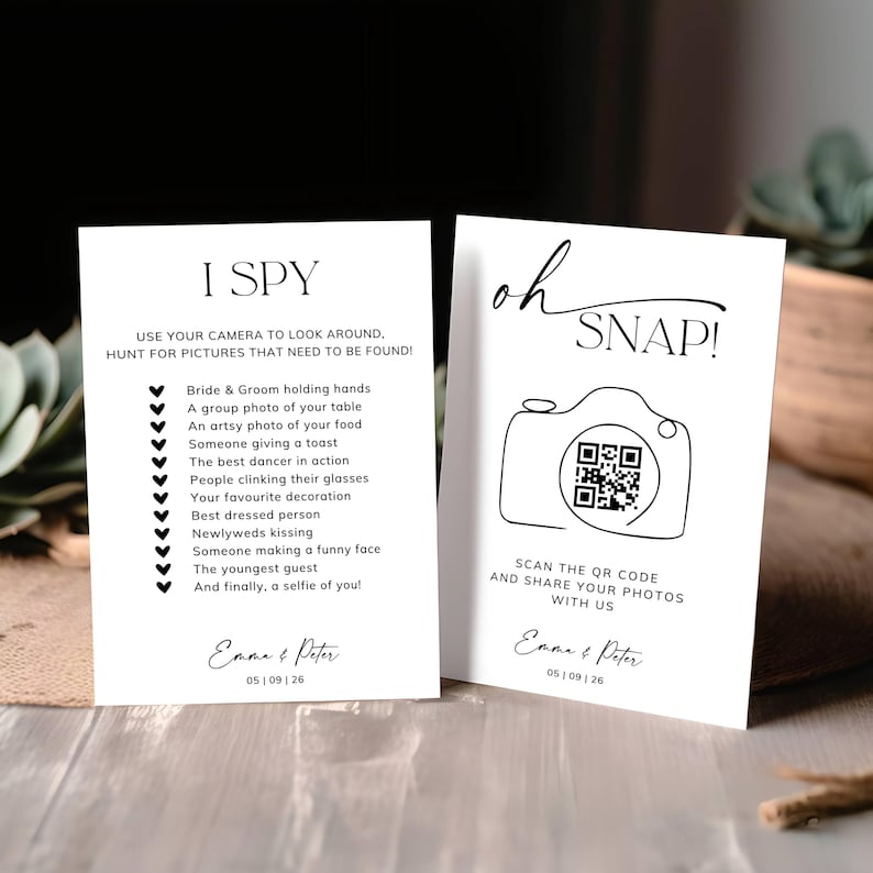 May include: Two white rectangular wedding cards with black text. The left card reads I SPY with a list of photo tasks. The right card reads oh SNAP! with a line-art camera icon, a QR code, and the names Emma & Peter with the date 05 | 09 | 26.