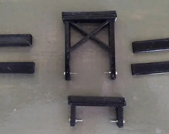 Puede incluir: Puente de caballete de tren modelo de metal negro con cuatro tablones de madera negra. El puente está hecho de metal y tiene un diseño simple.