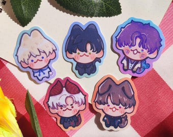 May include: A collection of six cartoon stickers featuring chibi-style characters with various hair colors and outfits. The stickers have a glossy finish and are arranged on a red and white checkered surface, with green leaves and a yellow flower in the background.
