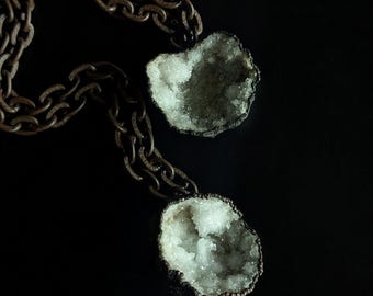 May include: A silver chain necklace with two crystal pendants. The crystals are clear and have a rough, natural texture.