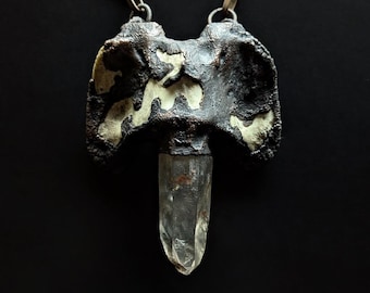 May include: A silver chain necklace with a pendant featuring a clear quartz crystal and a black and white patterned metal piece.