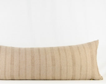 May include: A long, rectangular pillow with a beige and white striped pattern. The pillow is made of a woven fabric and has a subtle texture.