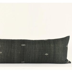 Peut inclure: Un long coussin rectangulaire noir avec un motif tissé subtil et de petits motifs géométriques blancs.