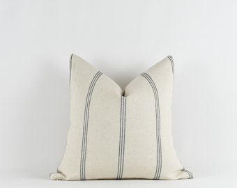 May include: A white pillow with black stripes. The pillow is made of a soft, textured fabric.