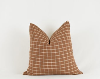 May include: A brown and white checkered throw pillow with a square pattern.