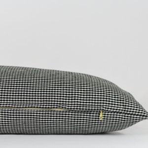 May include: A black and white gingham pillow with a zipper closure.