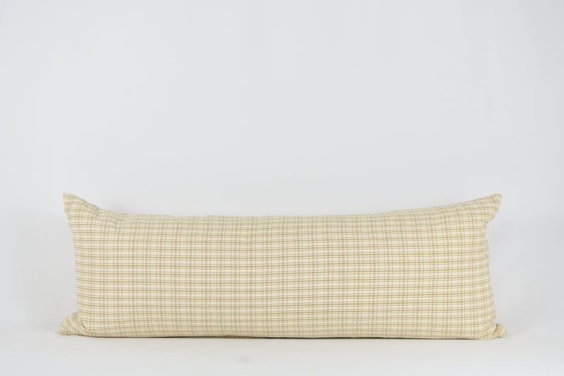 May include: A long, rectangular pillow with a beige and brown plaid pattern.