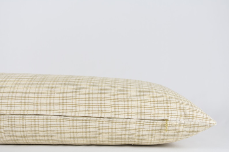 May include: A beige and brown checkered lumbar pillow with a zipper closure.