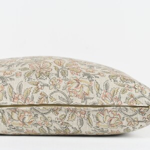 May include: A beige and pink floral patterned cushion with a zip closure.