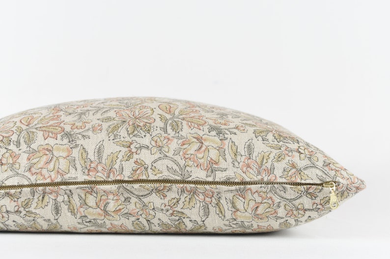 May include: A beige and pink floral patterned cushion with a zip closure.