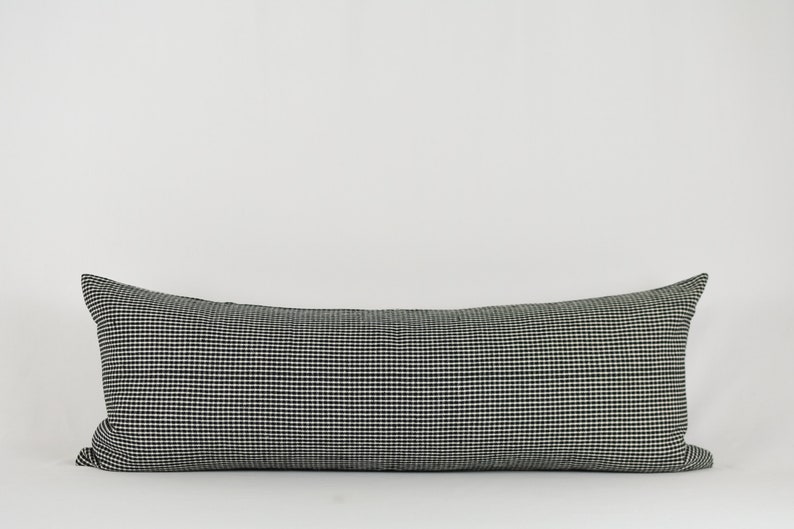 May include: A black and white checkered lumbar pillow. The pillow is rectangular and has a subtle sheen.