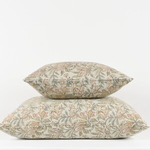 May include: Two decorative throw pillows with a floral pattern in shades of beige, brown, and orange.