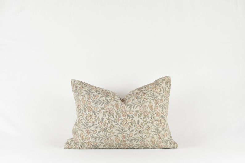 May include: A decorative cushion with a floral pattern in shades of beige, green, and orange.