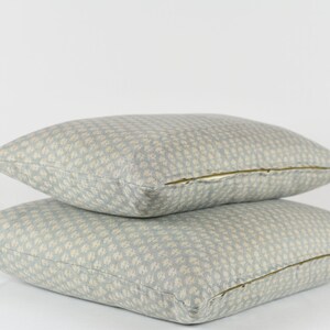 May include: Two light blue throw pillows with a white floral pattern. The pillows have a zipper closure.