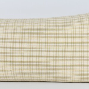 May include: A beige and white checkered lumbar pillow with a subtle sheen. The pillow is made of a soft, woven fabric and has a rectangular shape.