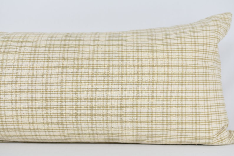 May include: A beige and white checkered lumbar pillow with a subtle sheen. The pillow is made of a soft, woven fabric and has a rectangular shape.