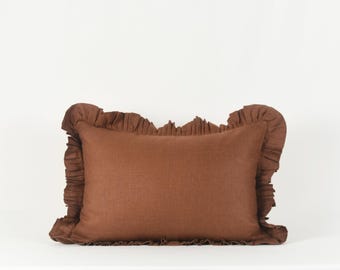 May include: A brown linen pillow with a ruffled edge.