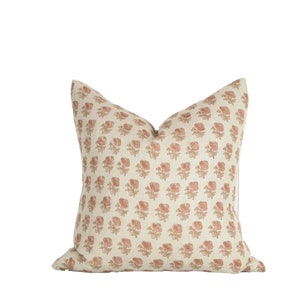 Może przedstawiać: Beżowa poduszka z kwiatowym wzorem w odcieniach r&oacute;żowego i brązowego.
