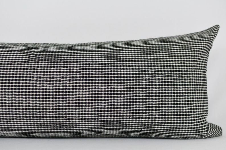 May include: Black and white gingham lumbar pillow. The pillow is made of a soft, woven fabric with a subtle sheen.