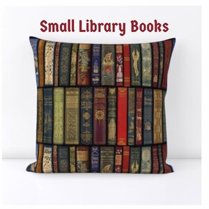 Puede incluir: Coj&iacute;n cuadrado con un dise&ntilde;o de libros antiguos apilados en varios colores, incluyendo dorado, rojo, azul y verde. El coj&iacute;n tiene el texto "Small Library Books" en una fuente burdeos.