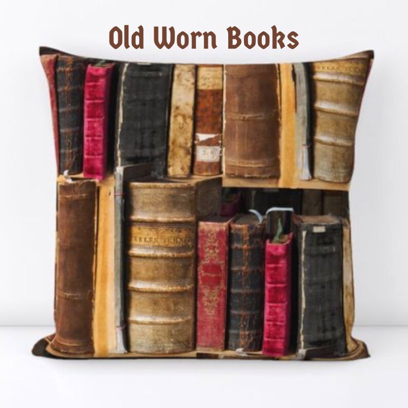 Puede incluir: Coj&iacute;n cuadrado con una impresi&oacute;n de libros viejos y desgastados. Los libros son de varios tama&ntilde;os y colores, incluyendo marr&oacute;n, negro y rojo. El texto "Old Worn Books" est&aacute; impreso en la parte superior.