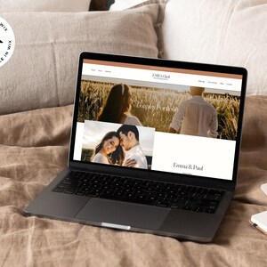 May include: A laptop computer displaying a website for a photography business called "Emma & Paul Photography". The website features a couple's portfolio with a photo of a couple in a field of wheat. The text "Couples Portfolio" is visible on the website.