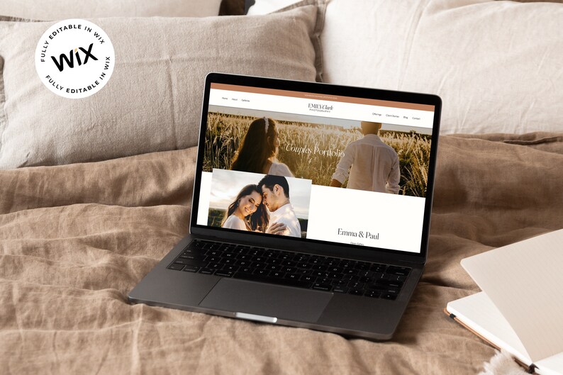 May include: A laptop computer displaying a website for a photography business called "Emma & Paul Photography". The website features a couple's portfolio with a photo of a couple in a field of wheat. The text "Couples Portfolio" is visible on the website.