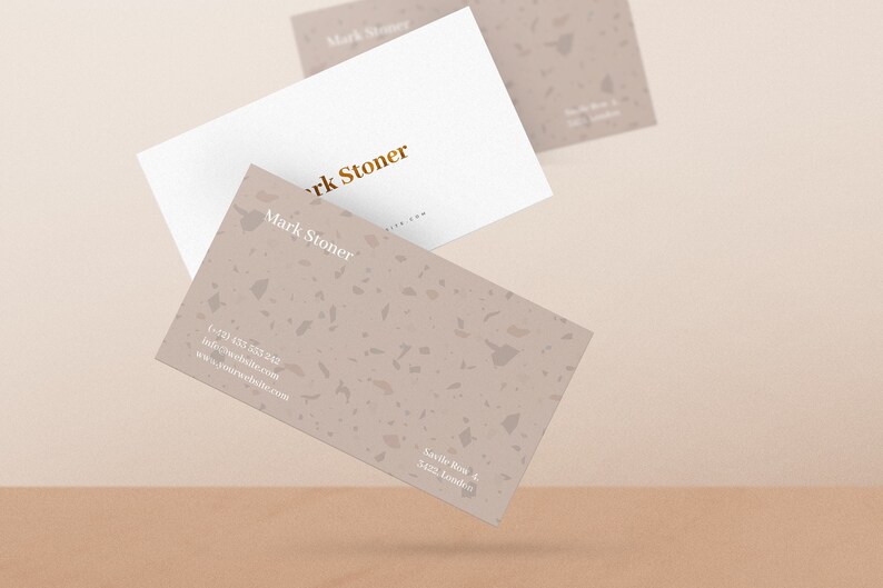 May include: Two business cards with a terrazzo pattern. The top card is white with gold lettering that reads "Mark Stoner". The bottom card has a light brown terrazzo pattern with white lettering that reads "Mark Stoner", a phone number, email address, website address, and the address "Savile Row 4, 3423 London."