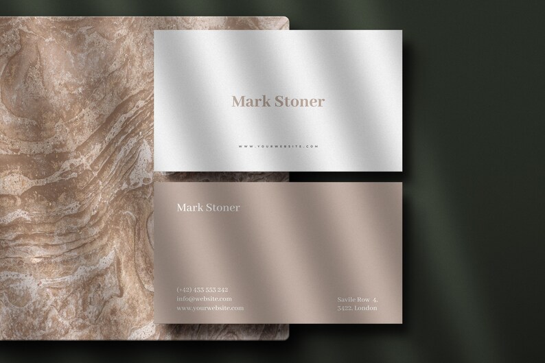May include: A white and a beige business card with the name "Mark Stoner" and contact information printed on them. The cards are on a brown marble background.