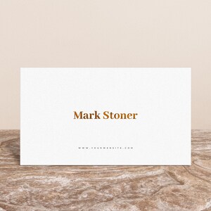 May include: White business card with the text "Mark Stoner" in gold lettering and the website address "www.yourwebsite.com" printed below.