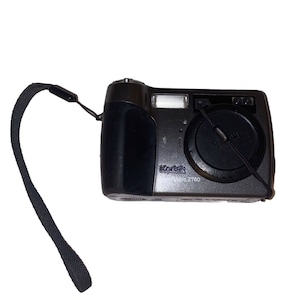 May include: A black Kodak Share Z760 digital camera with a lens cap and wrist strap. The camera has a built-in flash and a black grip. The Kodak logo is visible on the front of the camera.