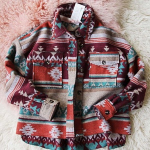 Peut inclure: Une chemise en flanelle &agrave; motif rouge, turquoise et marron avec un devant boutonn&eacute; et des manches longues. La chemise a un design d'inspiration sud-ouest.