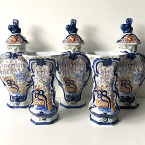 Puede incluir: Conjunto de cuatro jarrones de Delftware azul y blanco con diseños florales y paisajísticos. Cada jarrón tiene una tapa con un pomo de rana.