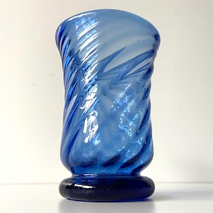 May include: A blue glass vase with a swirling pattern. The vase has a wide mouth and a narrow base.