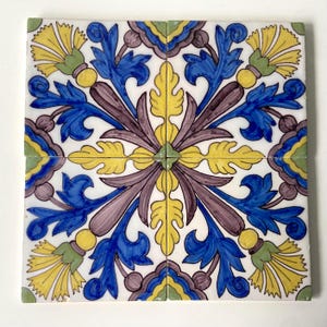 May include: Four square ceramic tiles with a floral pattern. The tiles are white with blue, yellow, green, and purple floral designs.