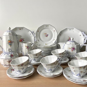 May include: A vintage porcelain tea set with floral designs. The set includes a teapot, creamer, sugar bowl, and six teacups and saucers.