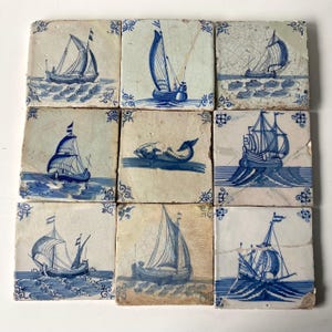 May include: Nine antique ceramic tiles with blue and white nautical designs. Each tile features a different sailboat or a whale illustration. The tiles are arranged in a 3x3 grid, showcasing a variety of maritime scenes.