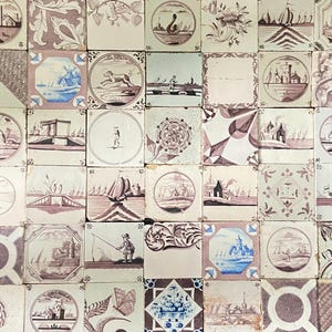 May include: A collection of antique ceramic tiles, each featuring unique hand-painted designs in shades of brown and blue. The tiles depict scenes of boats, landscapes, and floral patterns, creating a vintage aesthetic. The tiles are arranged in a grid.